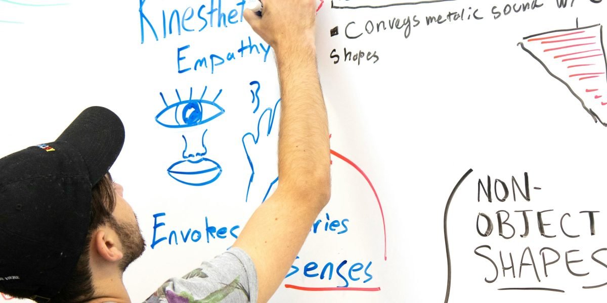 A person sketching complex ideas on a whiteboard, symbolizing the intricate magic systems and world-building of Mistborn.