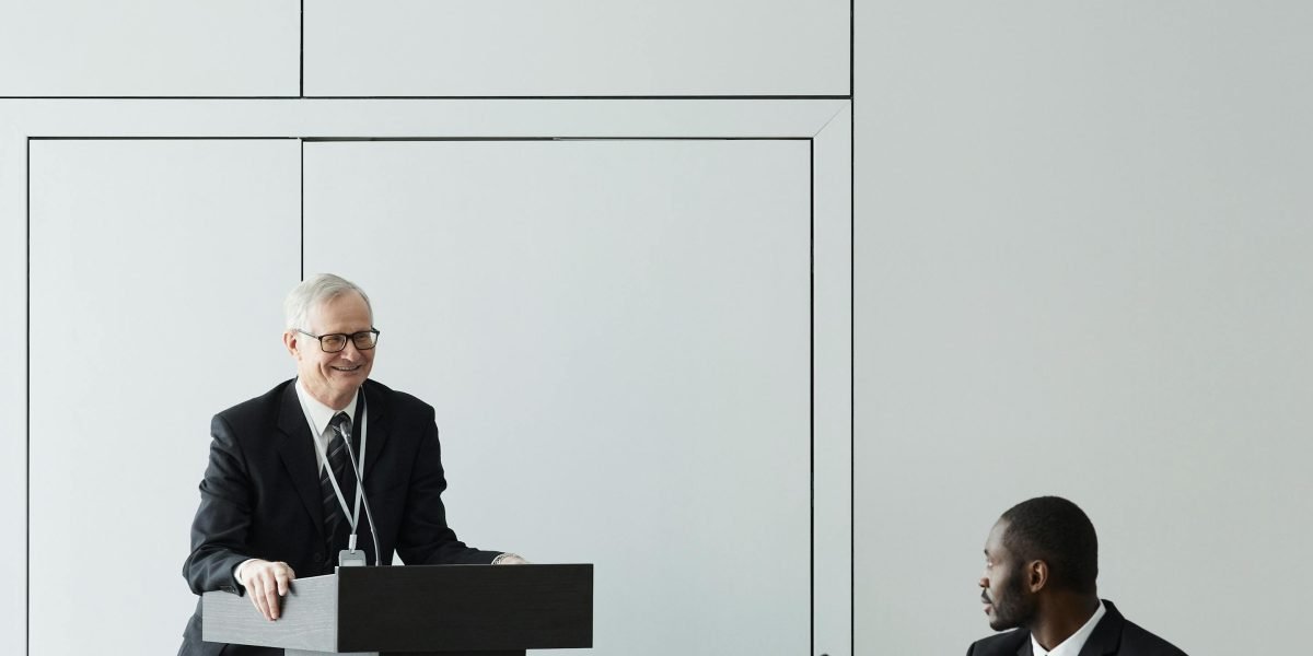 An author shares insights about their favorite funny novels during a literary conference, engaging with an audience.
