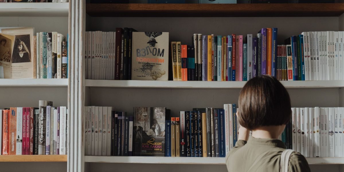 A reader contemplating a vast collection of Stephen King novels, illustrating the challenge of choosing where to start.