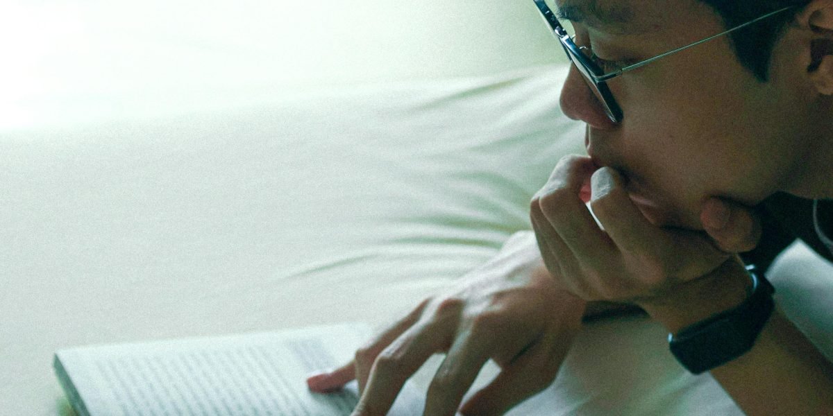 A person thoughtfully examining two books, symbolizing the choice between different literary experiences.