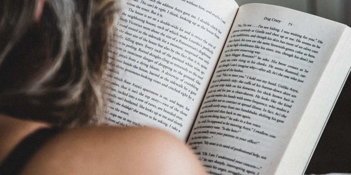 A person deeply immersed in reading a fantasy novel, highlighting the immersive quality of detailed world-building.