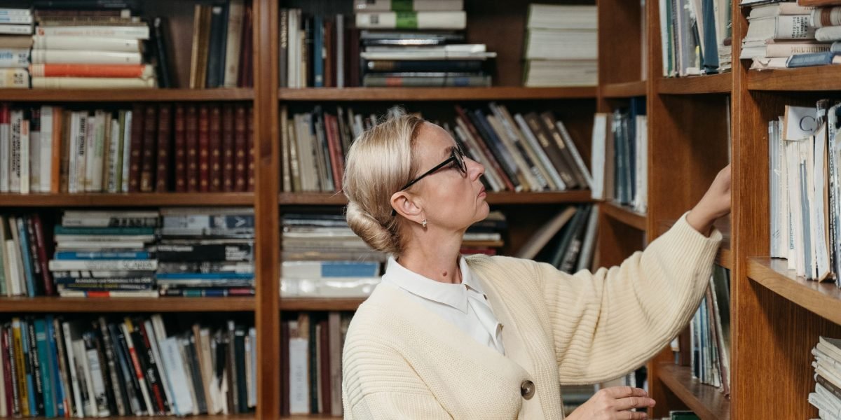 A reader thoughtfully choosing their next book from a selection of recommended titles after finishing a beloved series.